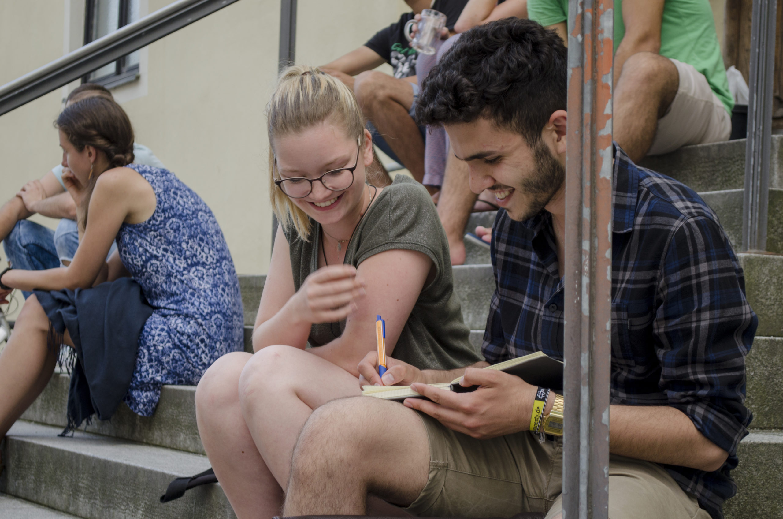 Leben und Lernen in Europa, Projekt 10-10-10 Junge Frau und junger Mann sitzen draußen auf Stufen und schauen gemeinsam in ein Buch